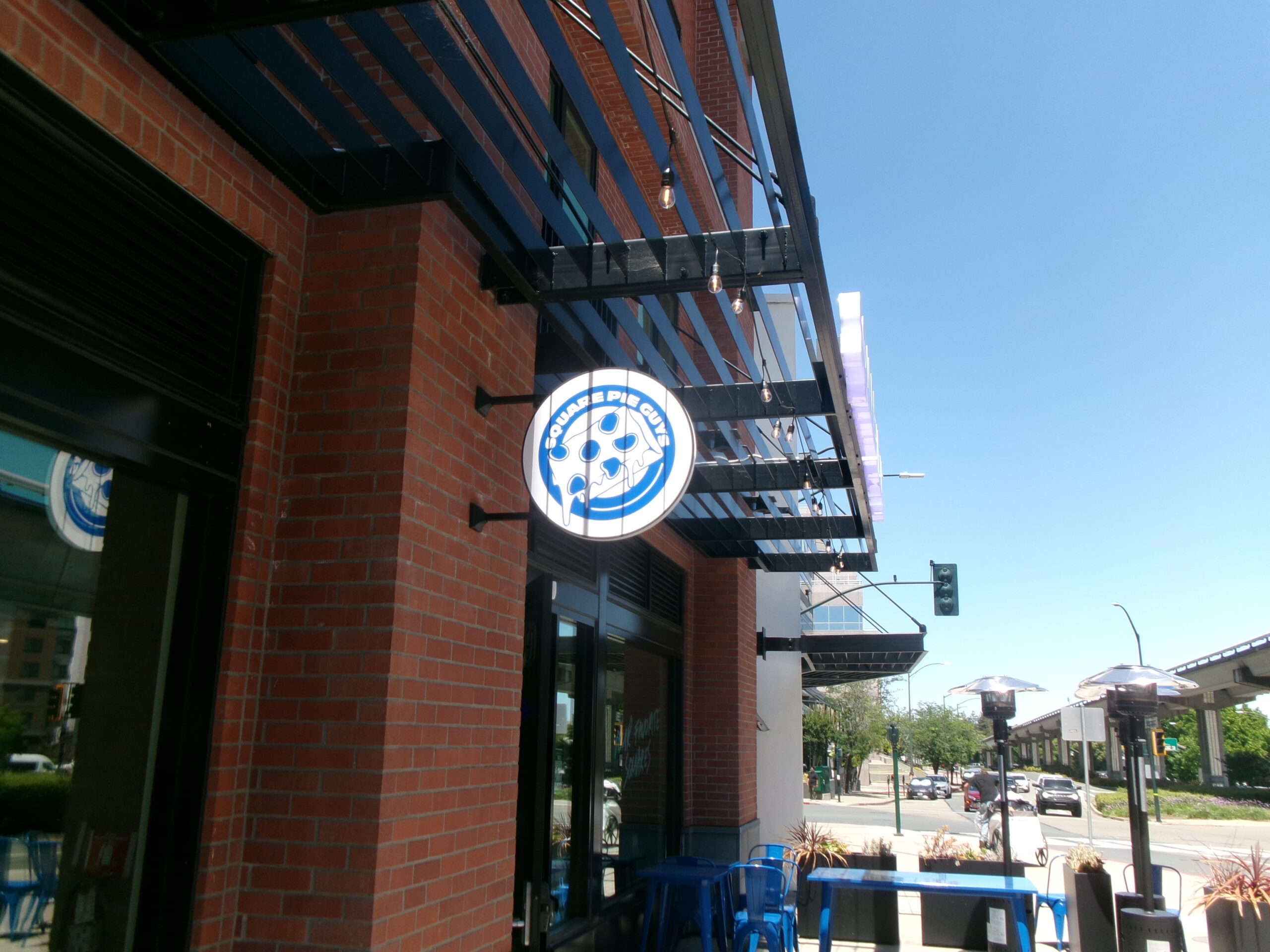 Square Pie Guys round blade sign on brick building exterior in San Jose, CA